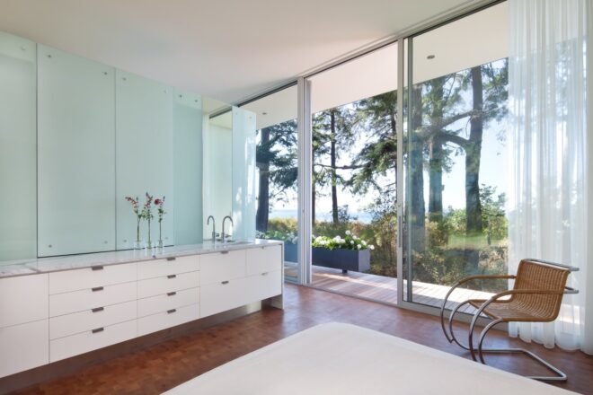 room with large white counter and sink and glass walls opening to a wooden patio