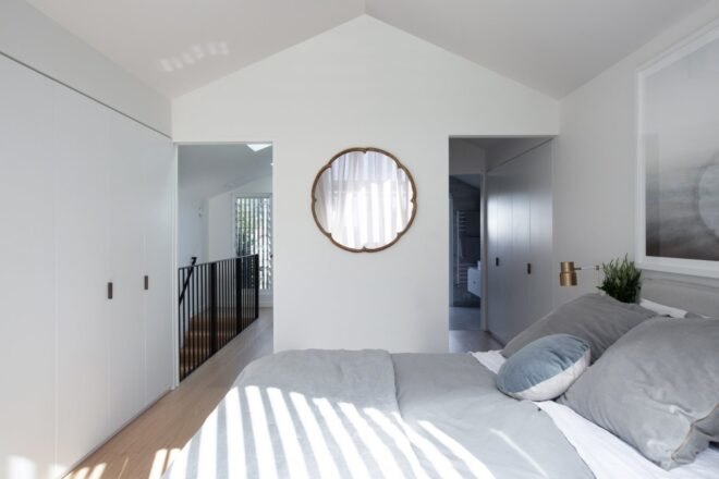 white bedroom with large round mirror on the wall