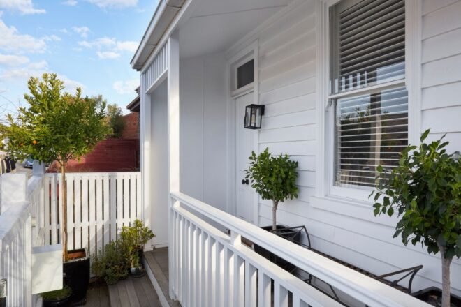white home with plants on narrow front porch