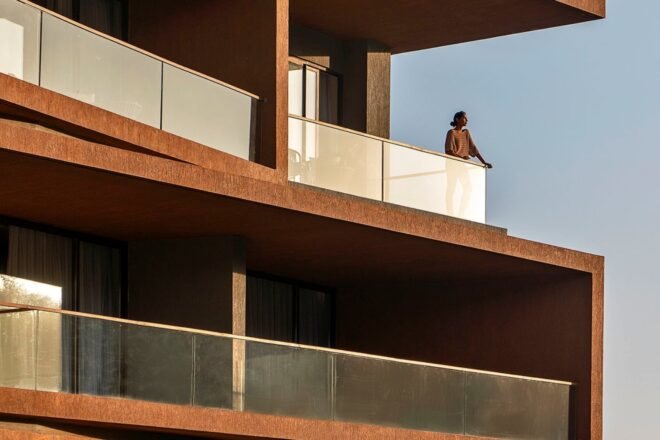 man standing out on balcony with glass balustrades