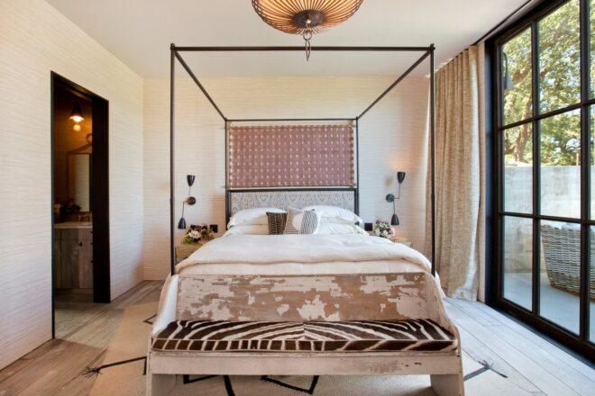 white four-poster bed with patterned bench at the foot