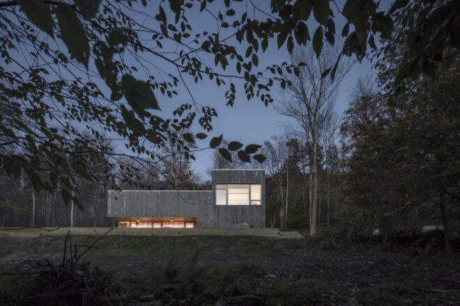 an evening shot of a gray rectangular building surrounded by trees