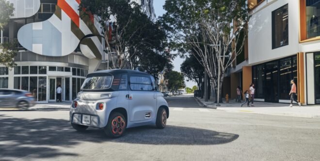tiny gray electric car driving on a street