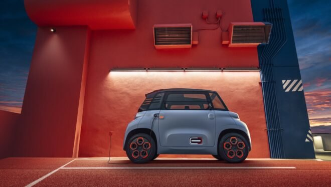 tiny gray electric car beside an orange building