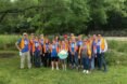 volunteers in orange vests standing in a group and smiling