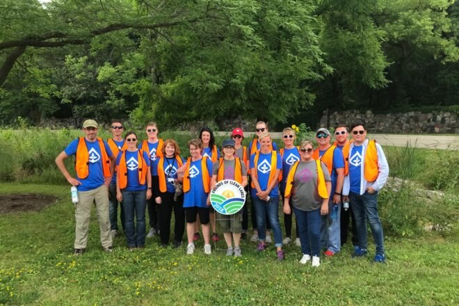 volunteers in orange vests standing in a group and smiling