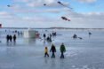 people walking and flying kites on a frozen lake