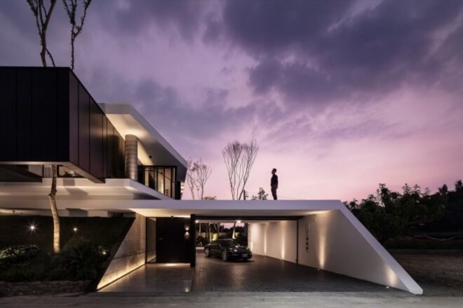 person standing on roof of black and white home during sunset