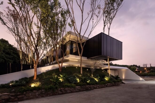 cantilevered black and white home at dusk