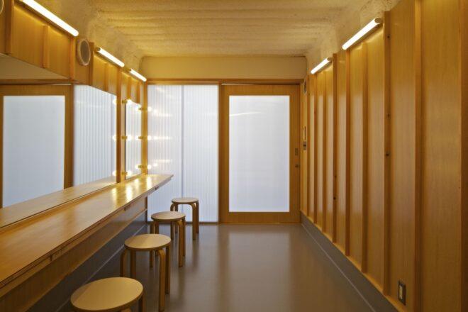 wood-lined shipping container interior with bar stools and a long narrow table