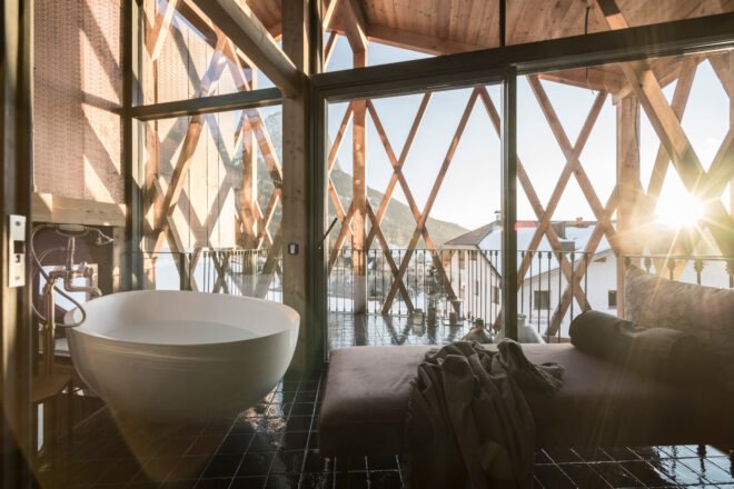 bed and soaking tub in room with glass walls