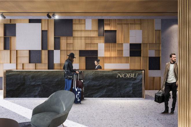 interior of a hotel lobby area, with a person in a hat checking in at a desk