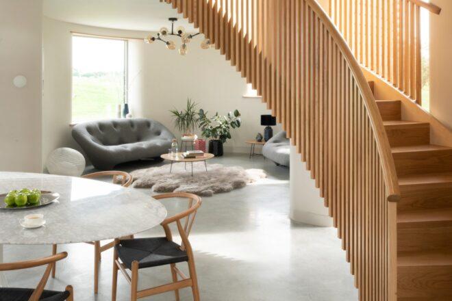 gray sofa and chair behind a circular wood staircase