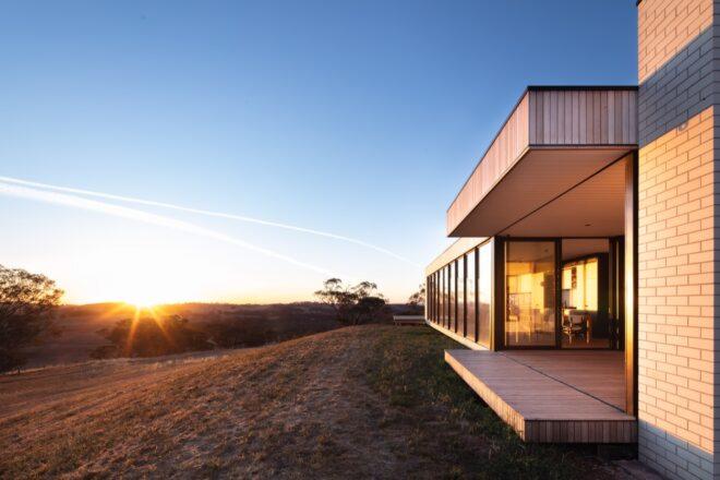 sun setting in the distance with a wood home in the foreground