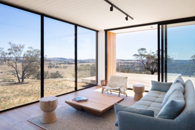 gray sofa and large wood coffee table facing a wall of glass