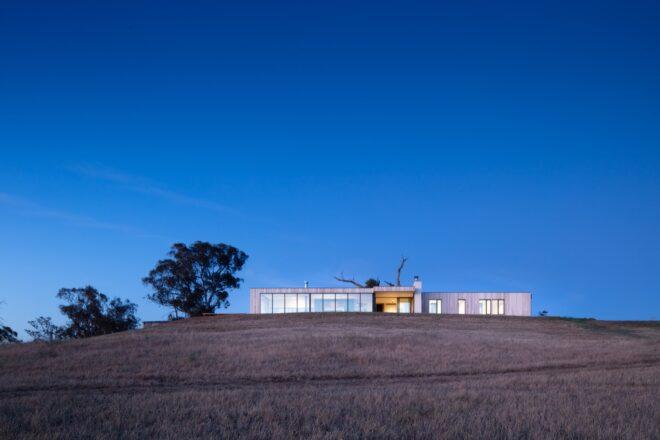 long prefab home on a hill at dusk
