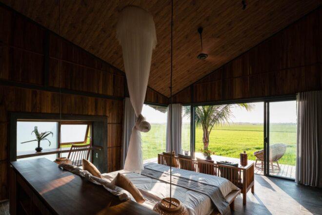 white bed facing glass wall inside a bungalow