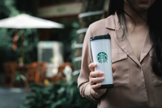 person holding white Starbucks-branded reusable cup