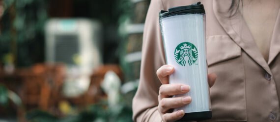 person holding white Starbucks-branded reusable cup