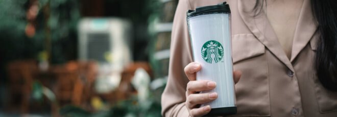 person holding white Starbucks-branded reusable cup