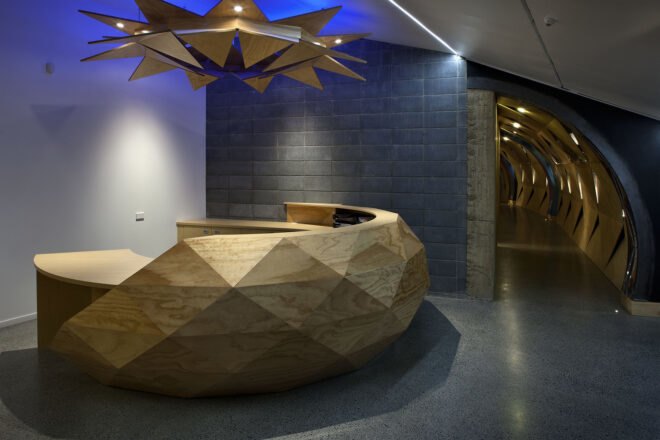 a curved desk with overhead light inside a building, with a hallway to the right