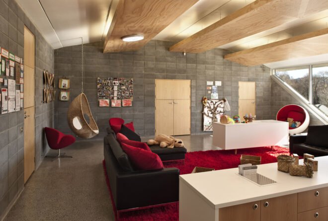 the interior of a room with red furniture accents and a hanging chair