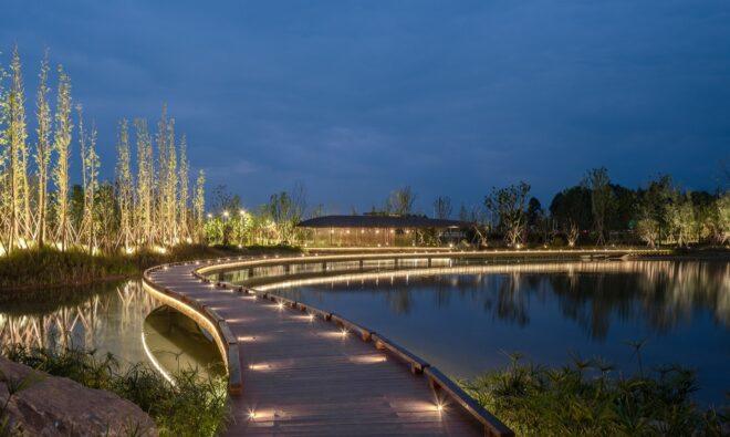 lit pathway near water at dusk