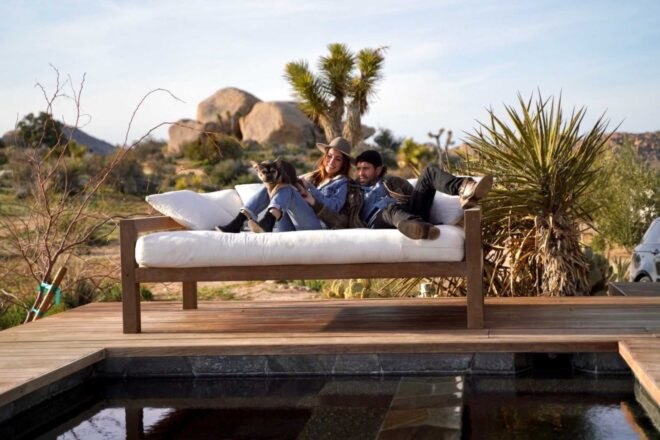two people and their dog sitting on a bench outside