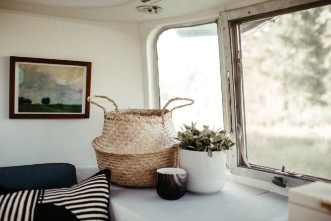 a decorative basket and plant on white shelf