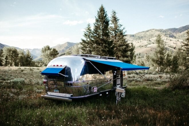 shiny airstream trailer with blue awnings