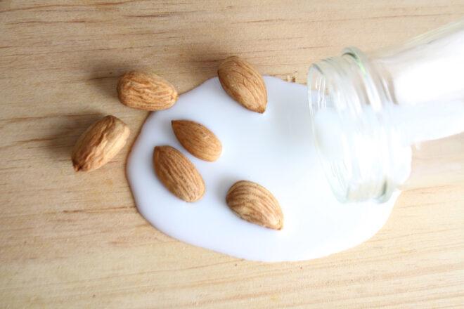 almonds near bottle of spilled almond milk