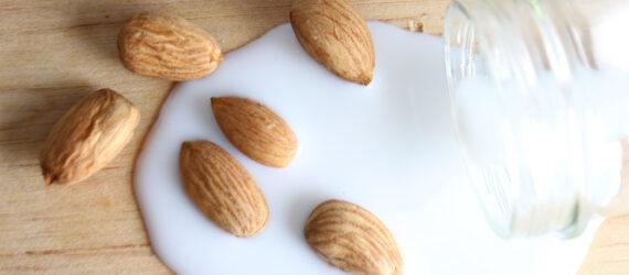 almonds near bottle of spilled almond milk