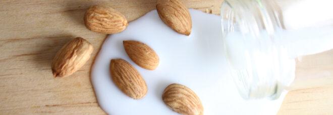 almonds near bottle of spilled almond milk