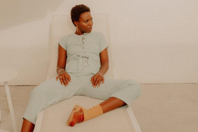 Person wearing cotton jumpsuit while lounging in a chair by the pool