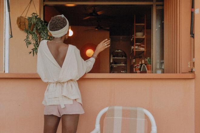 person wearing flowy white blouse and pink shorts