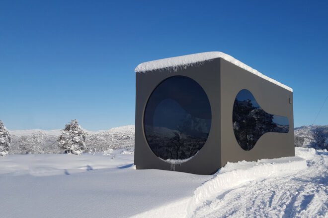 black cubic cabin with a large round window