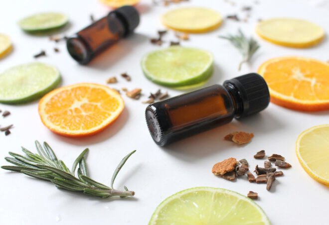 small brown essential oil bottles surrounded by slices of orange, lime, seeds and herbs