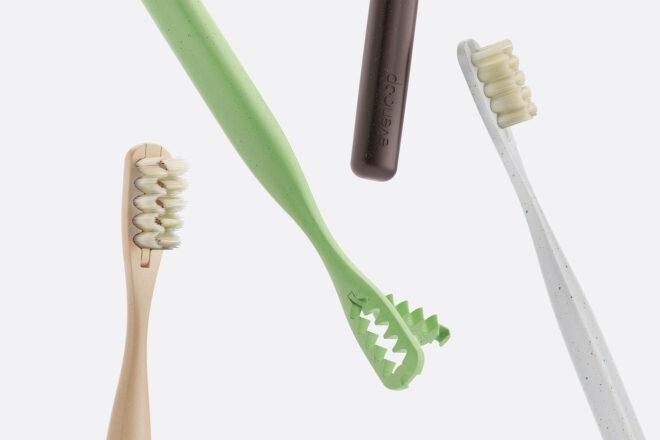 tan, white, black and green toothbrushes on white background