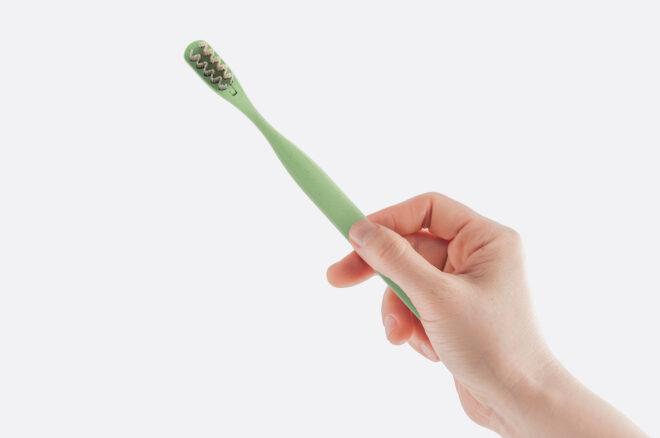 hand holding a green toothbrush