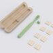 green toothbrush next to flat bamboo bristles and a compostable container