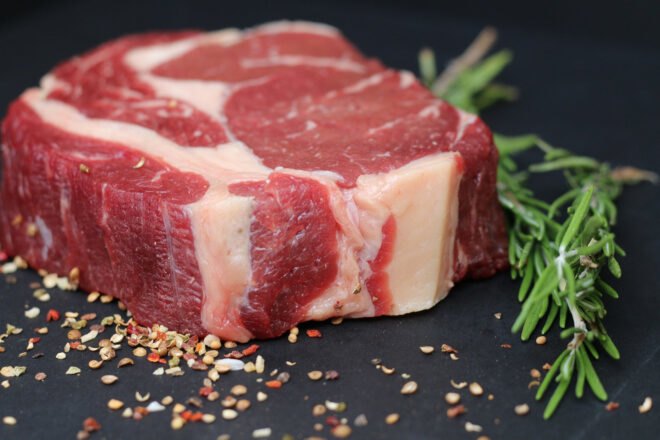 a steak surrounded by loose seasoning and a sprig of herb