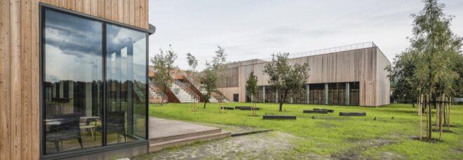a green lawn area in front of a wood paneled high school building