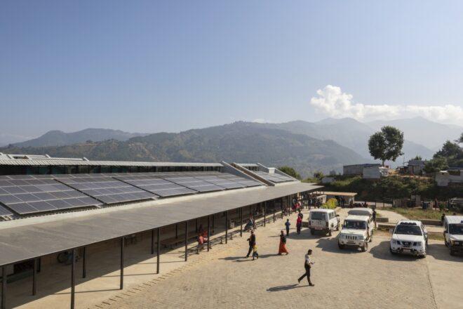 people walking near awning and building covered in solar panels
