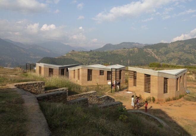 aerial view of rammed earth hospital buildings with mountains in background
