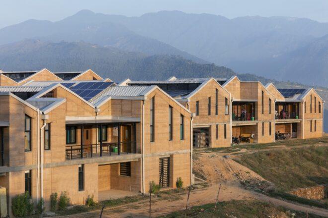 several rammed earth buildings with solar panel roofs