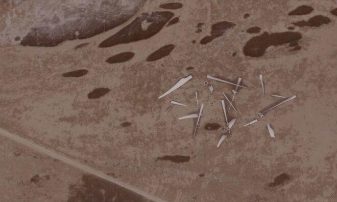aerial rendering of wind turbine blades scattered in a desert