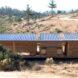a rectangular house with solar panels on the roof and wood facade