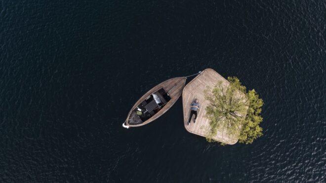 person lying on floating wood platform with a boat nearby