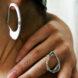 person wearing wavy silver hoop earrings and wavy silver ring