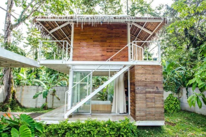 two-story structure made out of wood and glass with a thatched roof